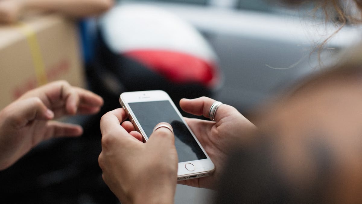 Hands holding a smartphone outdoors, showcasing technology in everyday life.